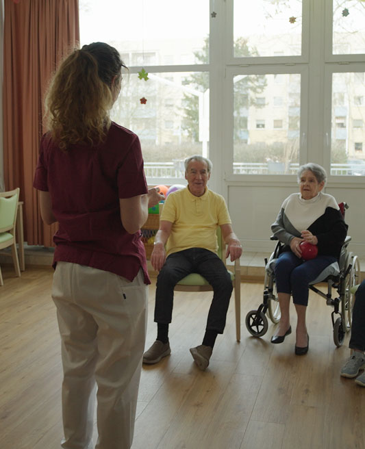 Care taker assisting a group of elderly people with sports 