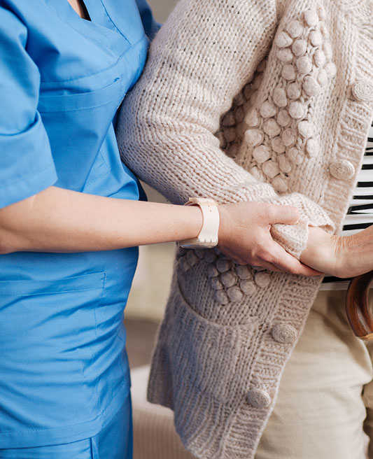 Care taker assisting an elderly person with a hand on her arm