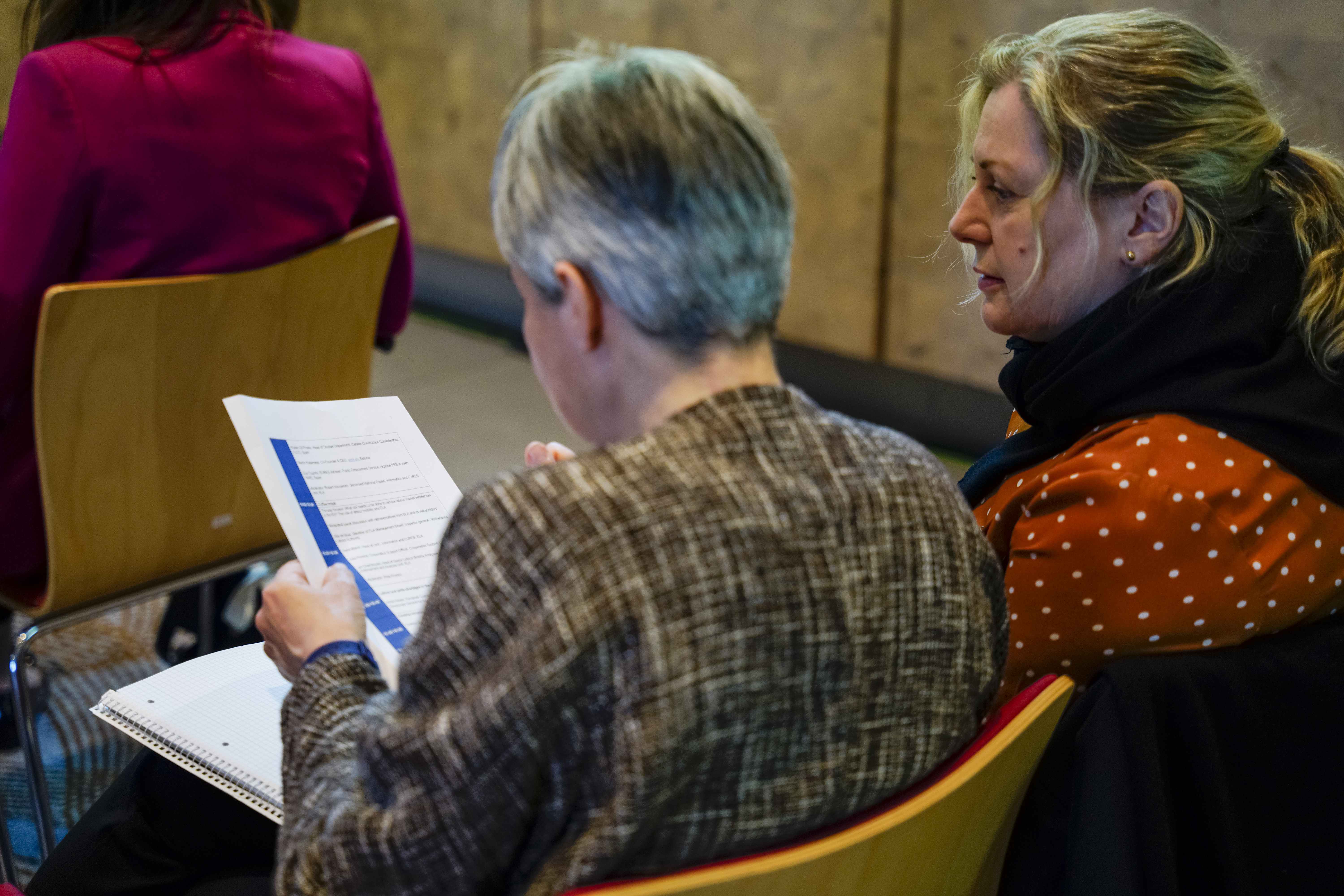 2 persons sitting in audience looking at the programme