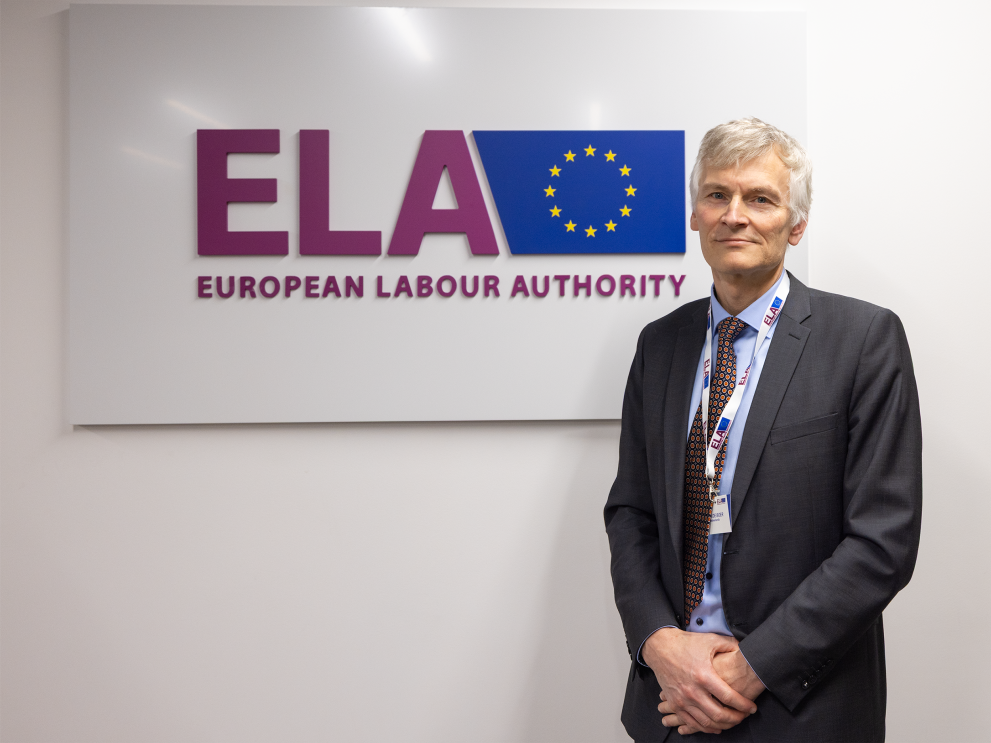 Man with grey hair standing in front of ELA sign