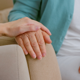 care giver holds older persons's hand